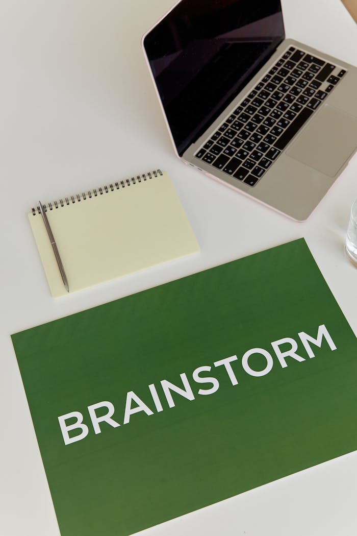Top view of a workspace featuring a laptop, notebook, pen, and a 'Brainstorm' sign.